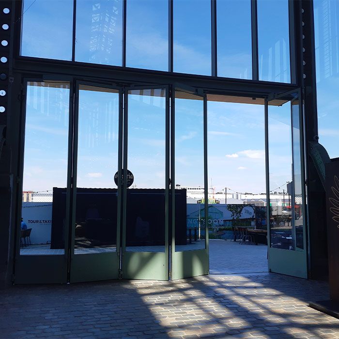 Automatische vouwdeur in glasstructuur van Gare Maritime op Tour & Taxis in Brussel, voorzien van toegangsautomatisatie.